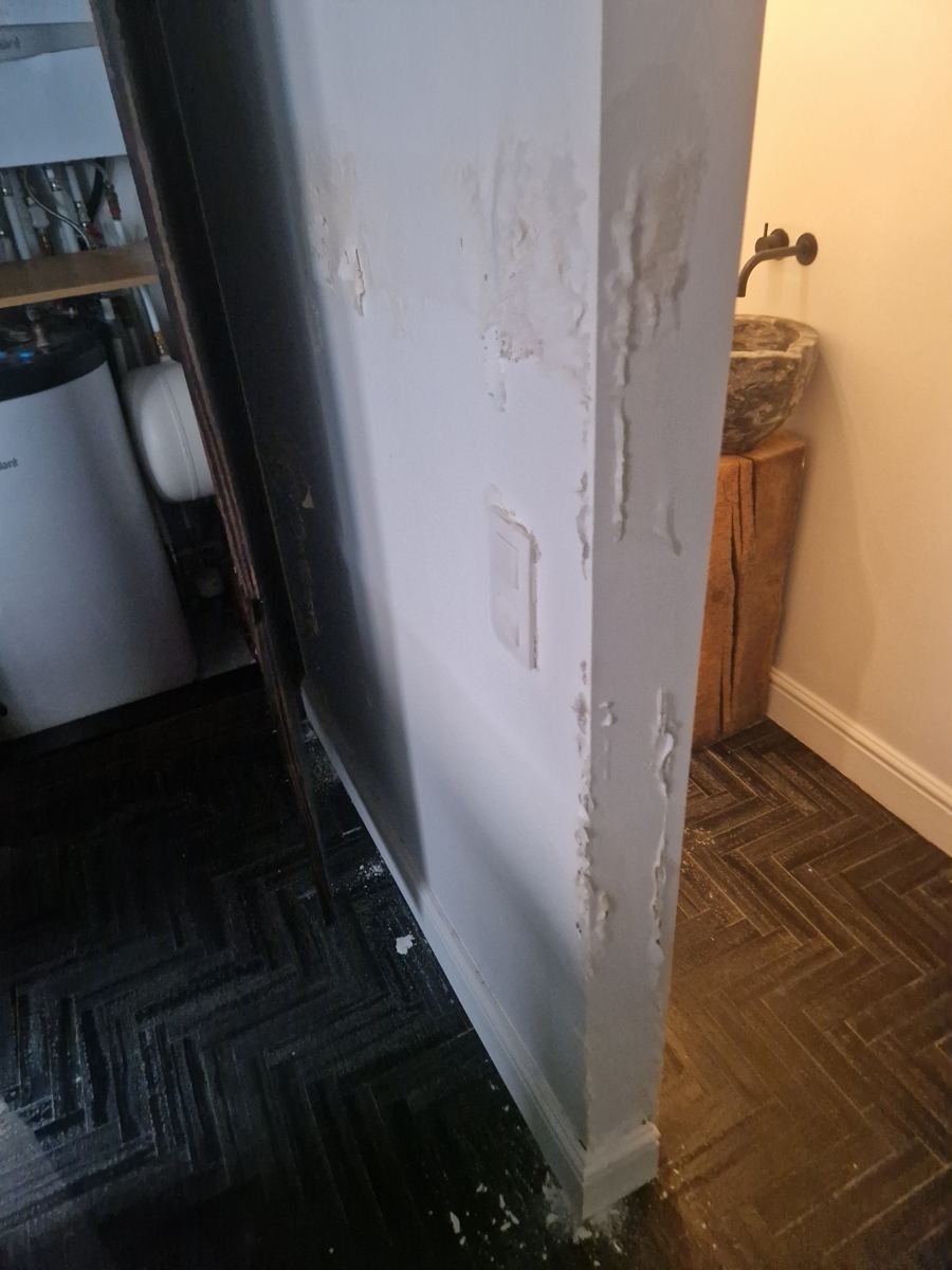 Afbladderende verf en pleisterwerk op een muur door vocht