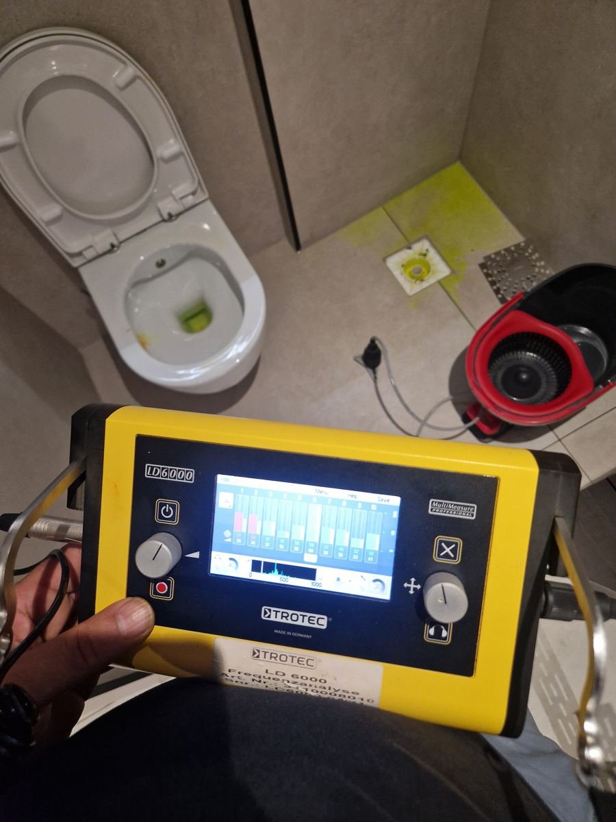 Lekdetector en markering op de vloer van een toilet tijdens onderzoek